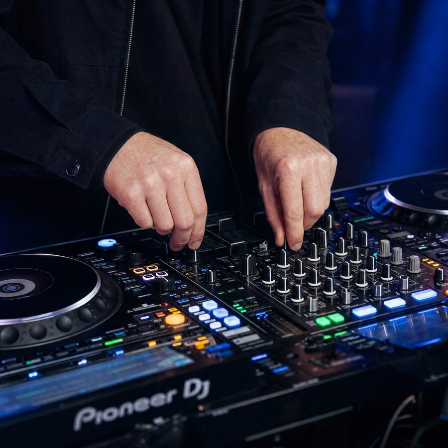 Mains d'un DJ de Rhums Event sur une table de mixage lors d'un événement